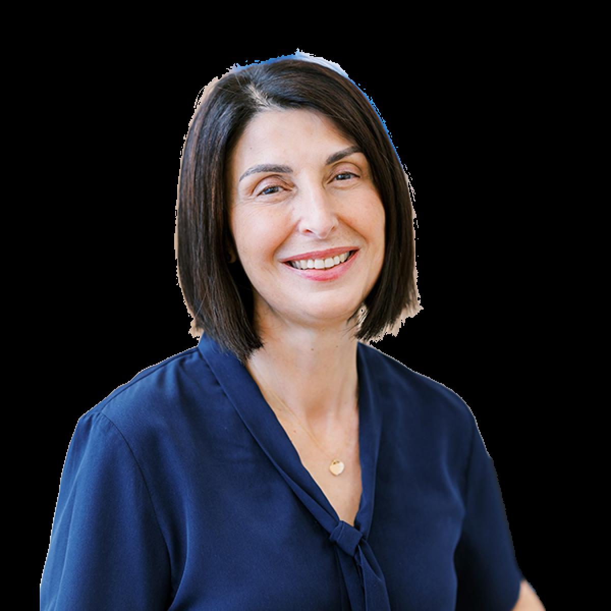 Professional headshot of female healthcare practitioner in blue medical uniform smiling at camera