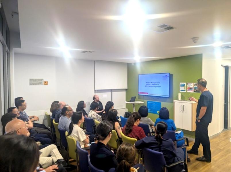 Healthcare professionals and staff attending a medical education seminar with presenter and digital display