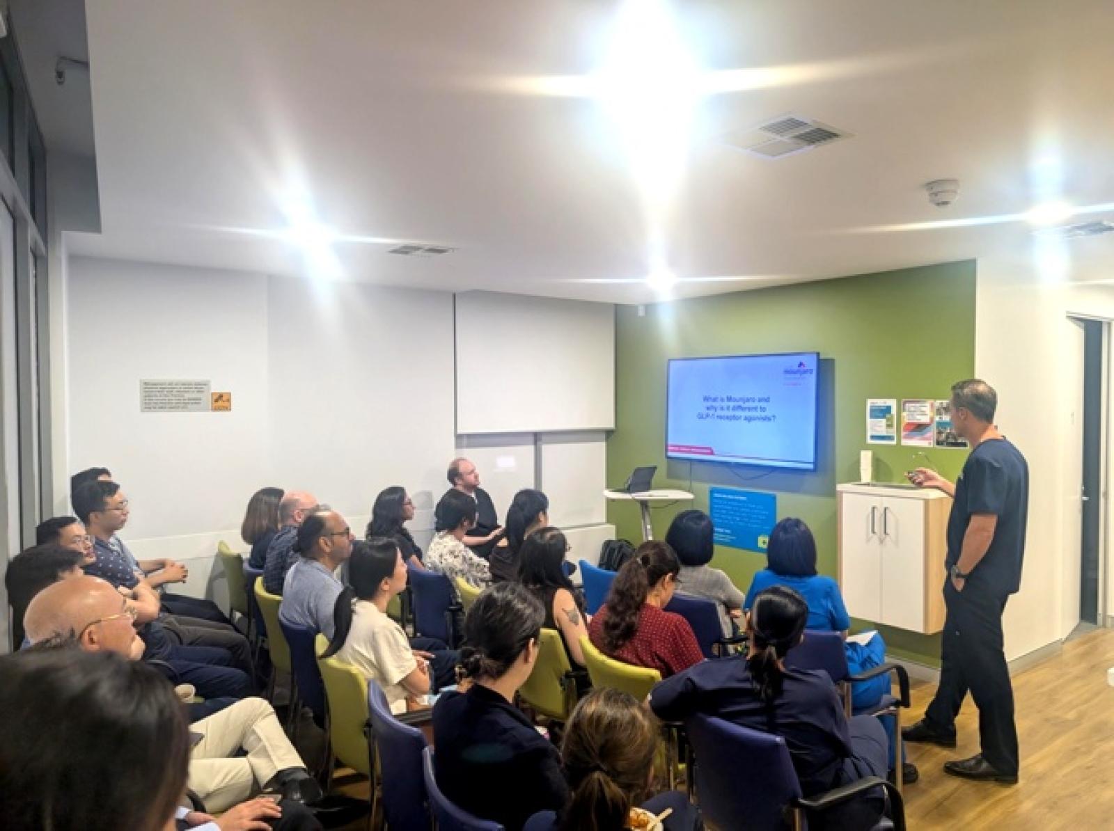 Healthcare professionals and staff attending a medical education seminar with presenter and digital display