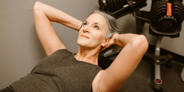 Mature woman performing strength training exercise with dumbbells in fitness facility